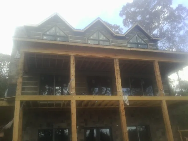 Dormers and porch framing on a large log home under construction — Roof Coating work by our crew in Geneseo
