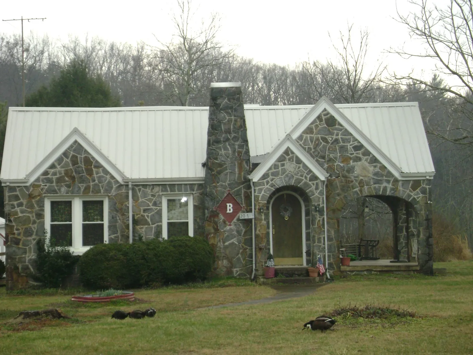 White metal roof on a stone cottage with steep gables in Geneseo
